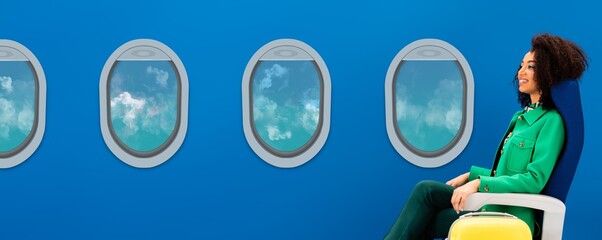 panoramic shot of smiling african american woman sitting on seat near travel bag and portholes on blue