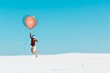 © LIGHTFIELD STUDIOS - man on sandy beach in vr headset flying on balloon against clear blue sky