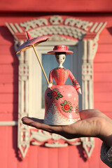 Wall Mural - Old russian traditional national handcraft, ethnic ornamental handicraft. Vintage wooden toy, Gorodets painting: lady with umbrella. Souvenir from Russia. Folk art, culture. Pink color. Carved window