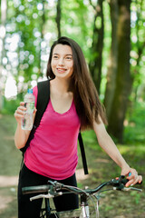 Wall Mural - Female cyclist on a bike, with bottle of water, drink, sport women in the forest