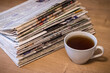 selective focus of the cup of tea stacking newspapers folded place on wooden table