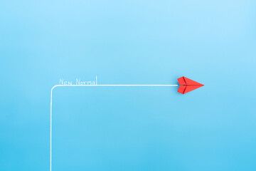 New normal concept with Red paper plane in new direction on blue background