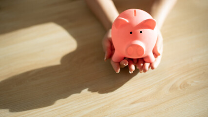 people hands hold support piggy coin bank with copy space, insurance investment money concept