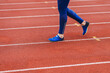 Young fitness woman in blue shoes and blue leggings walking on running court or treadmill. Girl in blue sport wear close-up to shoes running court background. Health exercise life style