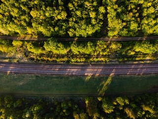 Sticker - Aerial shot of rail tracks surrounded by forests under the sunlight in Germany