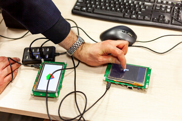 Man tapping, interacting with an lcd touch screen display on a single board microcontroller Progamming open source hardware micro controller apps technology concept, electronics, software developement