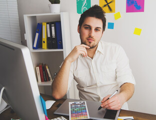 Young Handsome Graphic designer using graphic tablet to do his work at desk