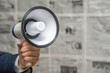 A man holding a megaphone on background of newspapers. News message concept