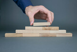 Fototapeta  - Male hand stacks wooden blocks. The concept of business development and growth.