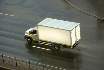 A truck with a white body is driving on an asphalt road, a place for the inscription