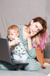 © Aleksei Zakharov - A young woman works at home with a laptop, along with a child.the son wants to communicate with his mother, they make noise and interfere with work.isolation during the coronovirus pandemic