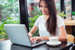 © PK Studio - Portrait of a happy woman using a smart phone and a laptop sitting in a table