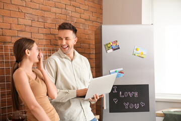 Wall Mural - Young woman with laptop in kitchen