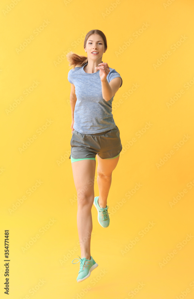 Sporty running young woman on color background