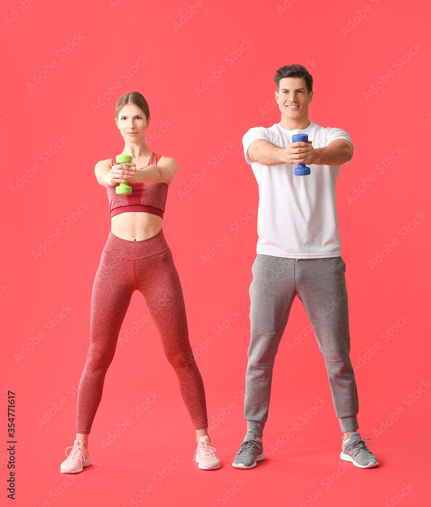 Sporty young couple training on color background