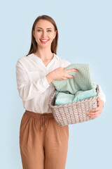 Wall Mural - Young woman with clean laundry on light background