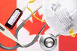Concept of Coronavirus or Covid-19 pandemic to use as background with Canada Canadian country flag and medical blood test, stethoscope, surgical N95 mask, thermometer