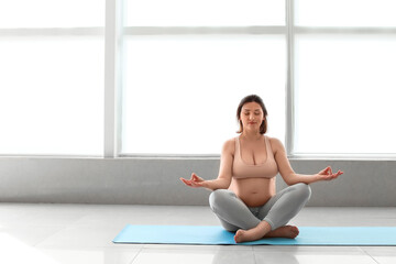 Wall Mural - Young pregnant woman practicing yoga in gym