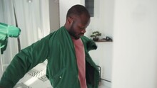 Black Handsome Guy Getting Dressed For Work In Front Of Mirror. Young African Man Wearing Jacket And Leaving House With Laptop For Work. Going Out. Lifestyle.