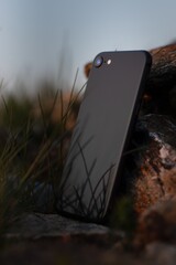 Sticker - Vertical closeup shot of a black smartphone leaned on a  stone