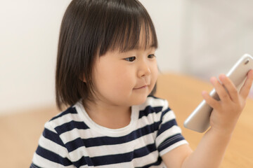 Sticker - 自宅の居間でスマートフォンを見る3歳の女の子