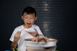Kid eating grilled meat on night background, grilled pork meat and seafood in chopsticks on hot steam smoke water from hot pan for cooking in party, roasted meat on night background for people eating 