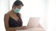 © chotiga - portrait of Asian woman sitting while working at home wearing protective mask. Business woman in quarantine for coronavirus wearing protective mask. Working from home New normal lifestyle.