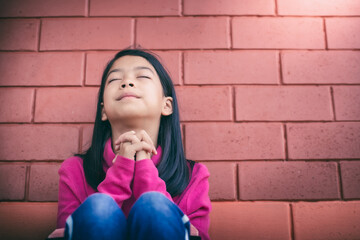 Sticker - Asian girl looking up while praying. Christian concept.