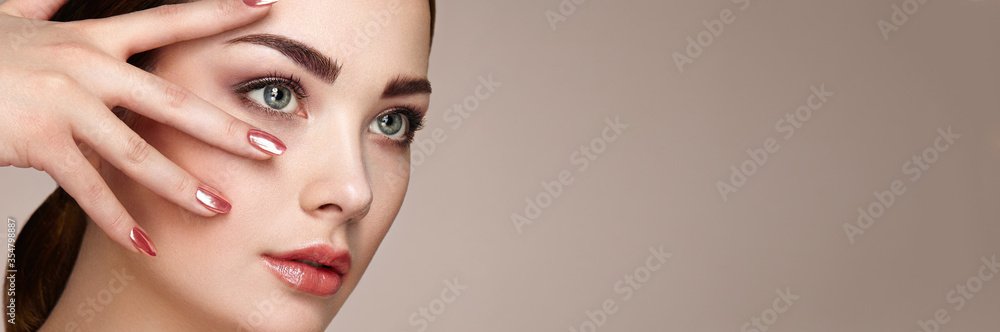Beauty brunette woman with perfect makeup. Red lips and nails. Perfect eyebrows. Skin care foundation. Beauty girls face isolated on beige background. Fashion photo - obrazy, fototapety, plakaty 