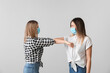 © Pixel-Shot - Young women greeting each other on light background. Concept of social distance during coronavirus epidemic