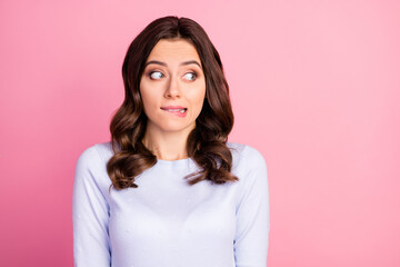 Wall Mural - Photo of attractive lady wavy hairdo biting lips look shy side empty space made wrong bad thing uncomfortable situation wear casual white pullover isolated pink color background