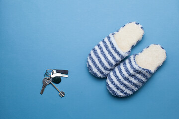 Two striped home slippers  and apartment keys isolated blue background