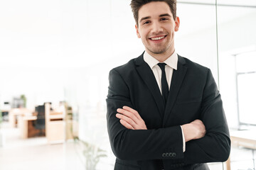 Wall Mural - Image of happy businessman smiling while standing with hands crossed