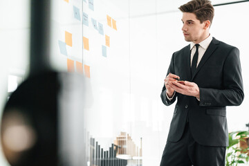 Sticker - Image of concentrated young businessman using stickers while working