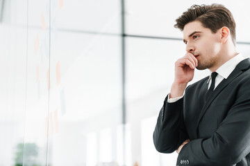 Poster - Image of thinking young businessman using stickers while working