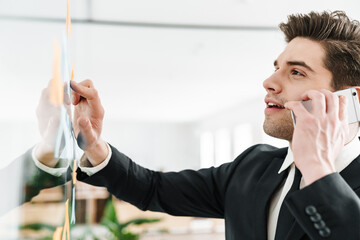 Sticker - Image of concentrated businessman talking on cellphone while working