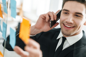 Sticker - Image of smiling businessman talking on cellphone while working