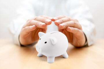 Poster - Protect your money. Small piggy bank covered by hands