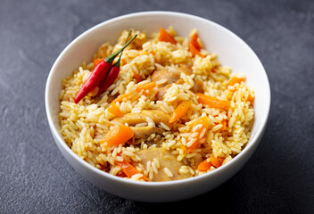 Wall Mural - Chicken and rice pilaf, plov on white bowl. Grey background. Close up.