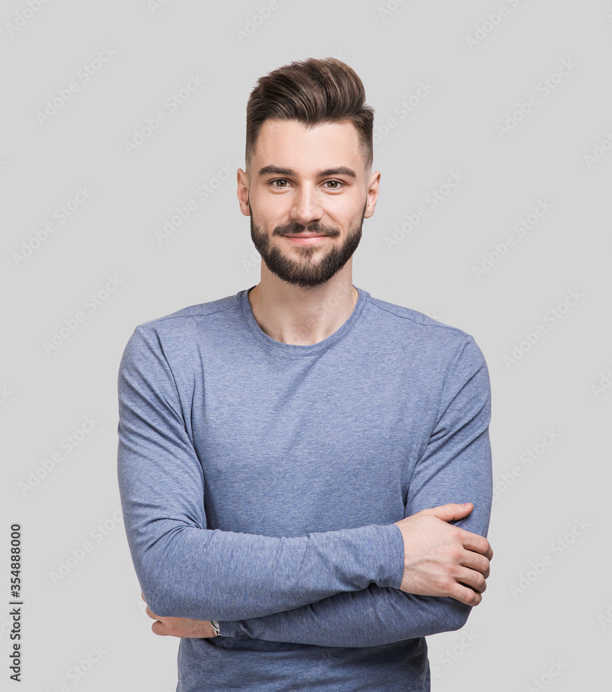 Portrait of handsome smiling young man with folded arms. Serious ...