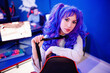 © Parilov - Woman gamer sitting table, playing online games on computer, neon color