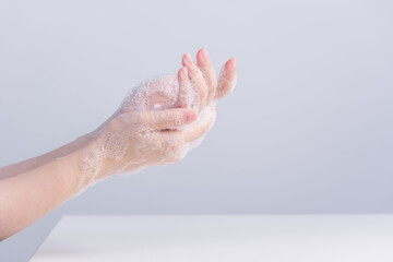 Washing hands. Asian young woman using liquid soap to wash hands, concept of hygiene to protective pandemic coronavirus isolated on gray white background, close up.