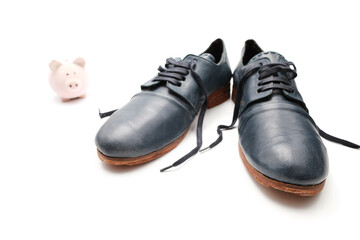 Close up view on small toy piggy bank and blue vintage leather shoes isolated on color background