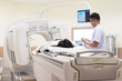 © arcyto - Asian radiologists explain treatment information to patients in x-ray room.CT (Computed tomography) scanner machine.High technology medical treatment equipment concept.