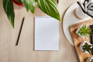 Poster - top view of green plants, blank notebook with pencils and pens in holder on wooden surface