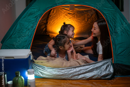 Asian woman playing and staying in tent with her daughter and having fun with camping tent in their bedroom a staycation lifestyle a new normal for social distancing in coronavirus outbreak situation