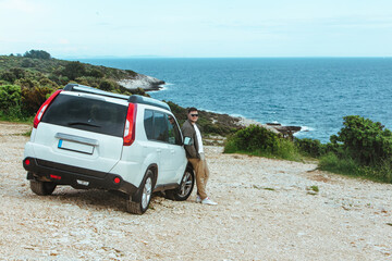 man lean on suv car enjoying view of the sea. summer road trip vacation