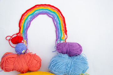 The multi-colored rainbow laid out of braids knitted by air loops. There are tangles at the bottom. View from above. A place for an inscription.