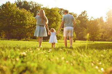 Wall Mural - Happy family walking on the grass in the summer park. Mother father and children playing in nature. Children Protection Day.