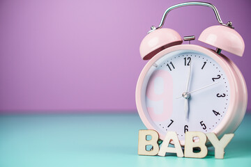 Time to baby. Detail close up of the old pink vintage alarm clock on colour background.